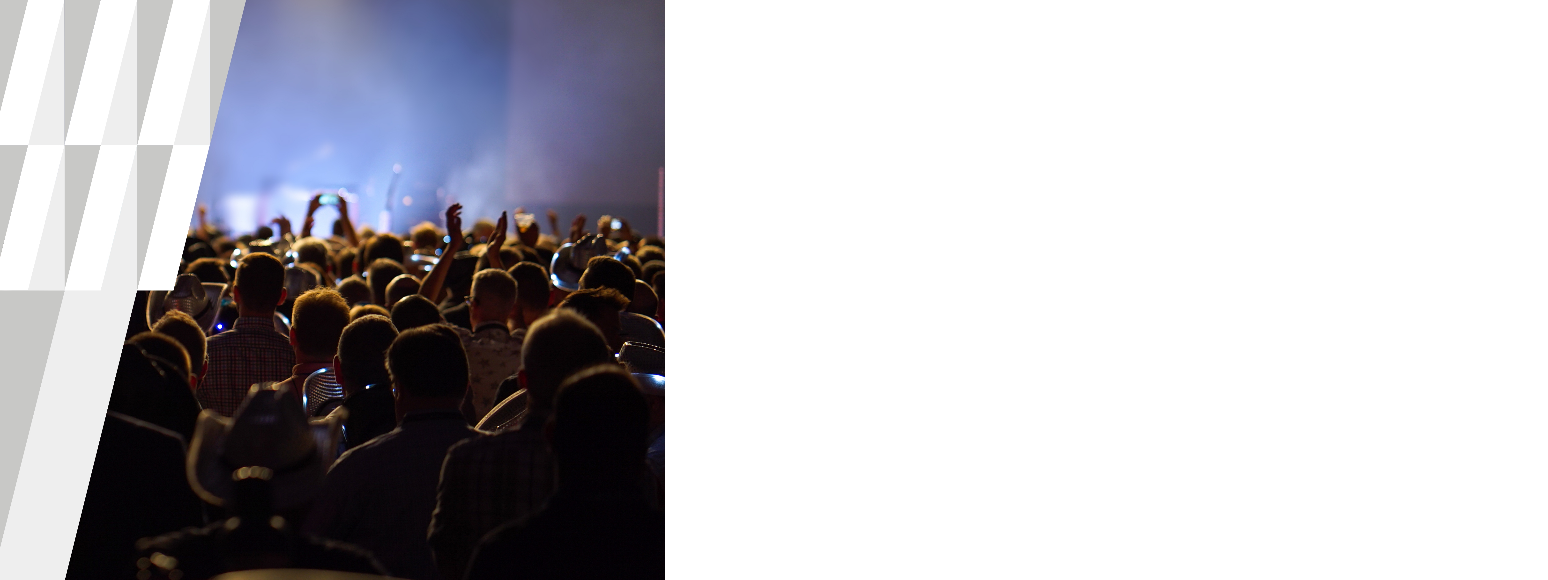 Aerial of crowd of people with hands in the air, facing stage.