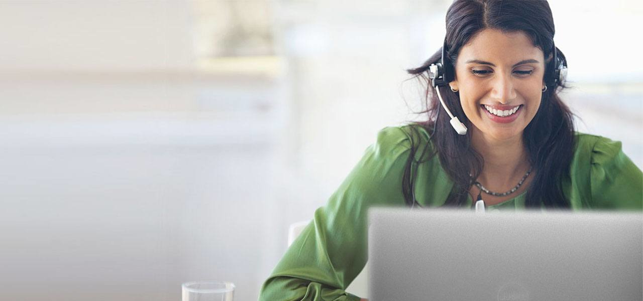 Woman in office setting with notebook and headset.