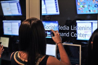 Woman using smartphone to take photo of Dell social media listening command center