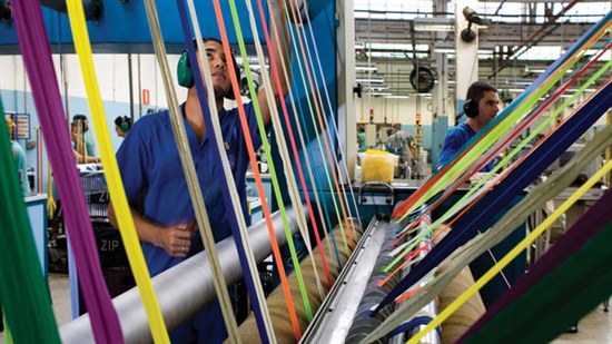 Coats Opti employee in Brazil facility with several colors of thread in machine