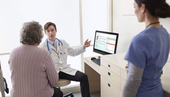A doctor consults with a patient while referring to information on an OptiPlex All-In-One
