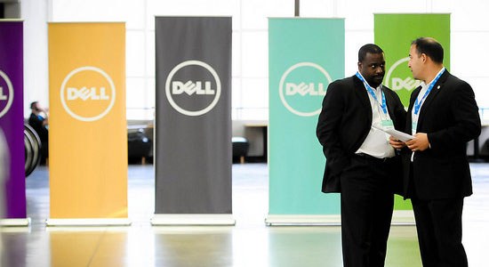 Photo of two men talking in front of several different colored signs with the Dell logo on them