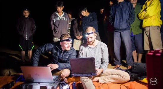 An expedition crew inside Son Doong cave watch as  Martin Edström and an assistant render images on their Dell laptops