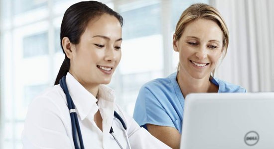 Two medical professionals look at data on a Dell laptop