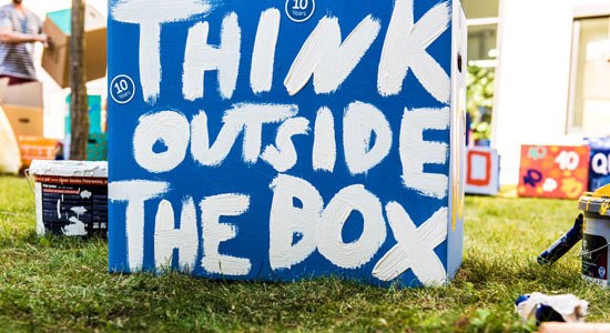 A box with writing painted on the outside that reads: think outside the box