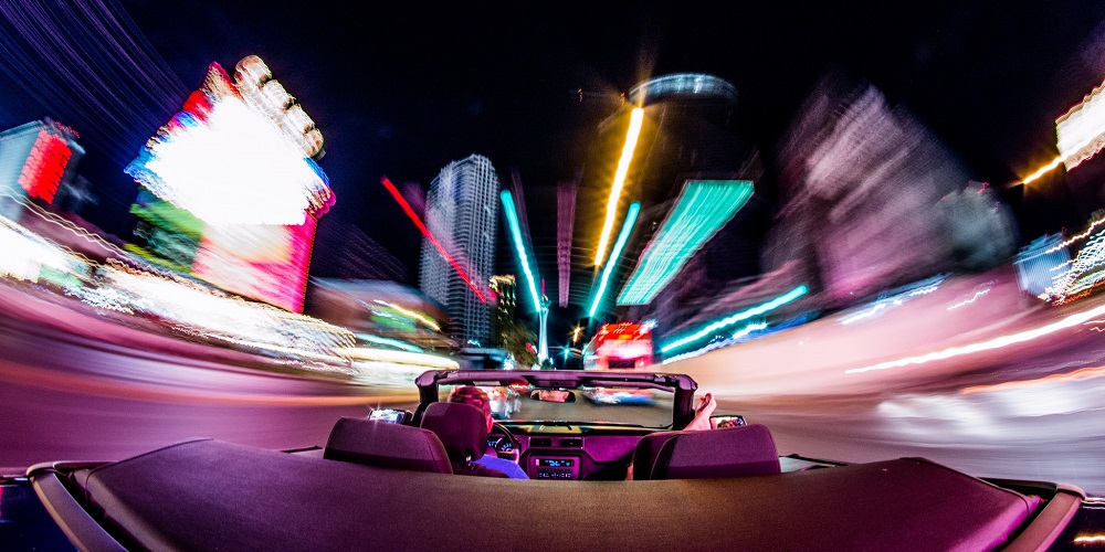 convertible car driving down a city street at night