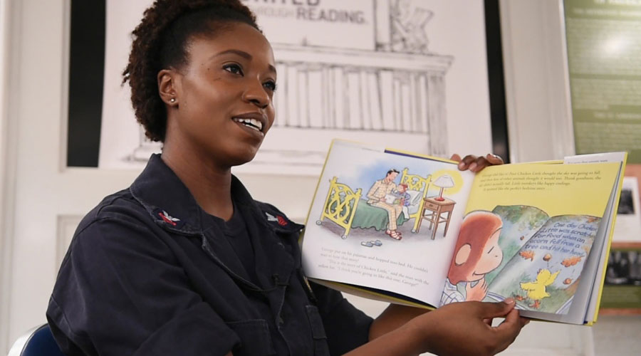 military woman reading book to children