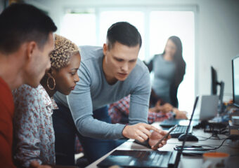 Closeup side view of group of mid 20's mobile application developers testing the code and fixing the issues.