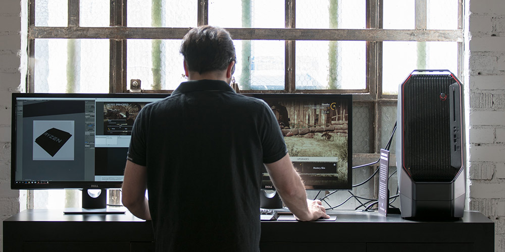 man standing in front of desk with Alienware desktop and Dell monitor