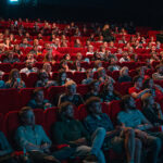 people sitting inside a movie theater Photo by Krists Luhaers on Unsplash