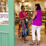 two women talking seen through the open door of a small business