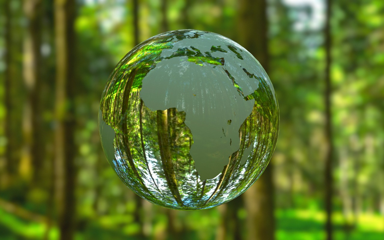 Earth globe in clear crystal with forest in background. Africa is facing camera and trees can be seen through crystal globe.
