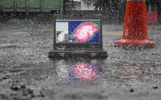 Rugged Latitude 7330 with hurricane satellite image on screen, on the ground in the rain