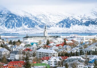 View of the skyline of Reykjavik Iceland, with the ocean and snow capped mountains in the distance.
