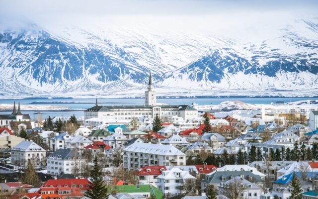 View of the skyline of Reykjavik Iceland, with the ocean and snow capped mountains in the distance.