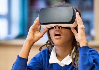 A young African-American girl is using virtual reality goggles.
