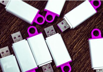 Several USB keys with white and magenta colors on a table.