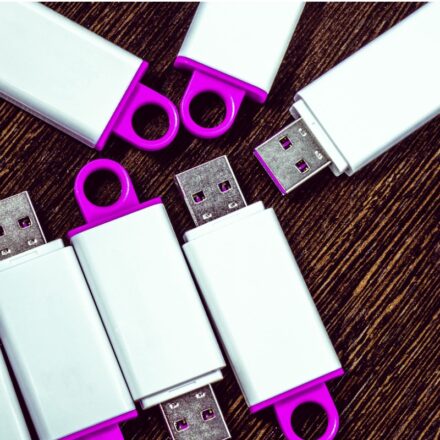 Several USB keys with white and magenta colors on a table.
