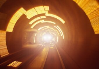 High speed movement in tunnel, with a light in the distance. In light yellow and darker orange colors.
