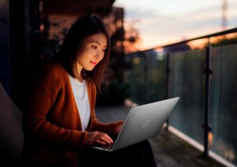 Woman sits outside at sunset working on an XPS laptop.