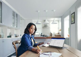 Woman working remotely at her dining room table, using technology provided through Dell Lifecycle Hub.