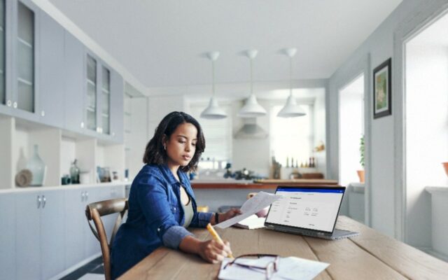 Woman working remotely at her dining room table, using technology provided through Dell Lifecycle Hub.