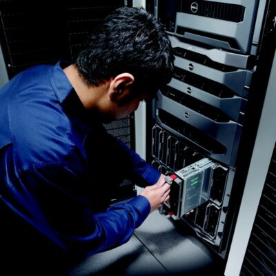 Man in blue shirt pulls a blade server out of server rack.
