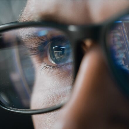 IT professional monitoring security applications, closeup on their eyes and glasses.