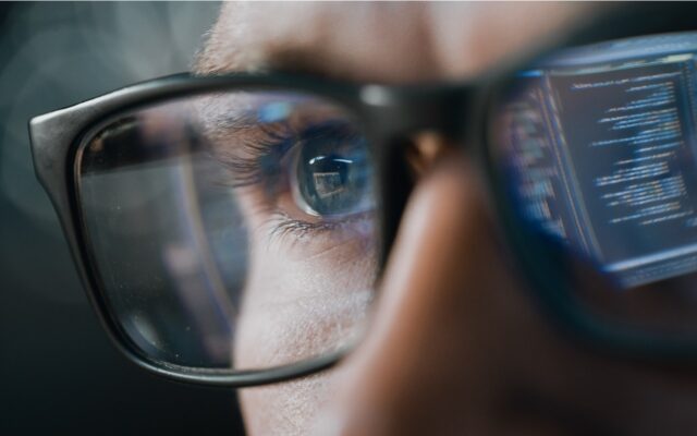 IT professional monitoring security applications, closeup on their eyes and glasses.