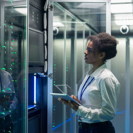 Female IT professional checking status of servers in data center.