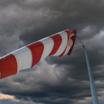 Windsock, orange and white striped, indicating strength of wind strength before an approaching storm, which is appearing in the background.