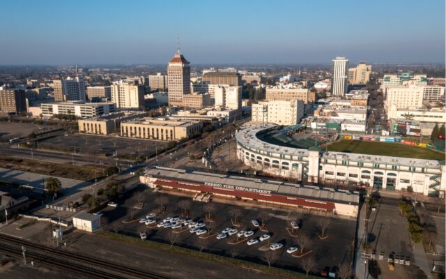 Ariel view over Fresno, California, with fire station and baseball stadium and commercial buildings against the daytime skyline.