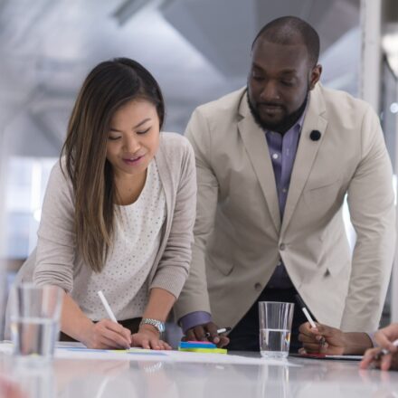 Asian female and Black man in business casual attire sign business documents.