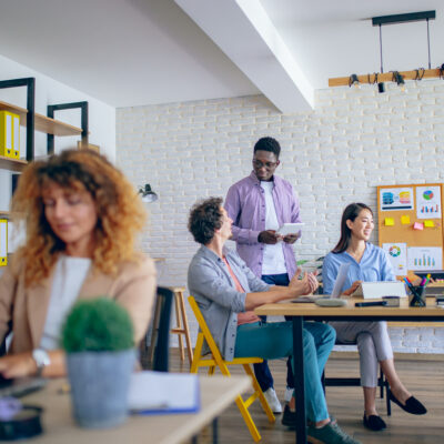 Businesswoman using laptop at modern office, her colleagues are working in the background